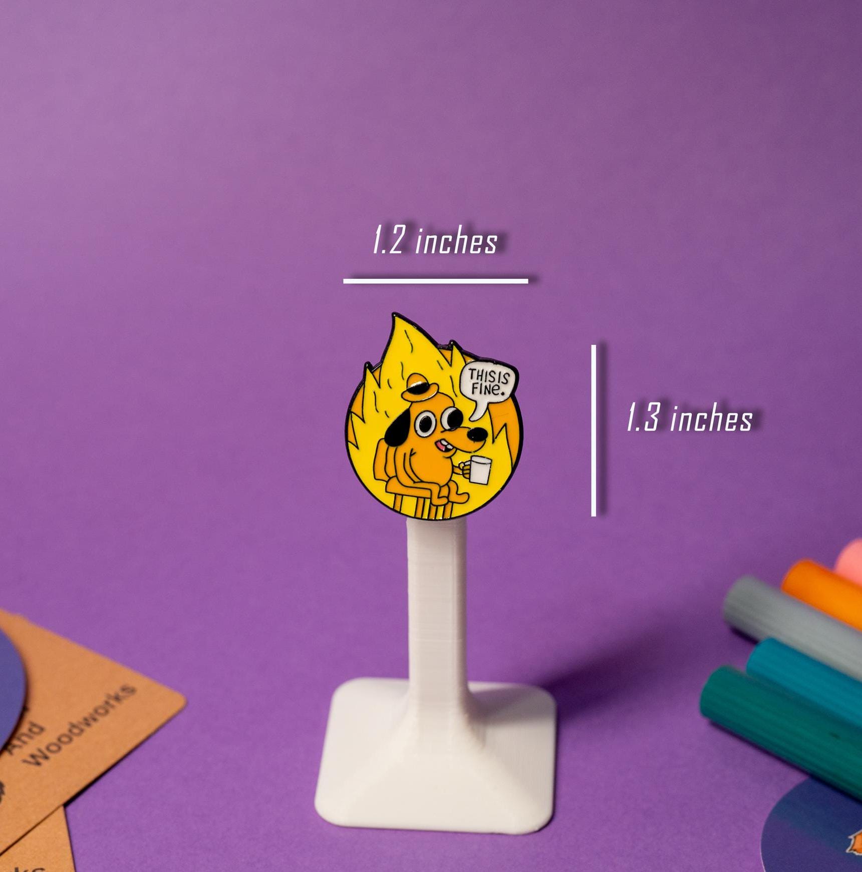 Funny enamel pin of the This Is Fine meme, displayed on a stand, ideal for quirky and relatable accessories.