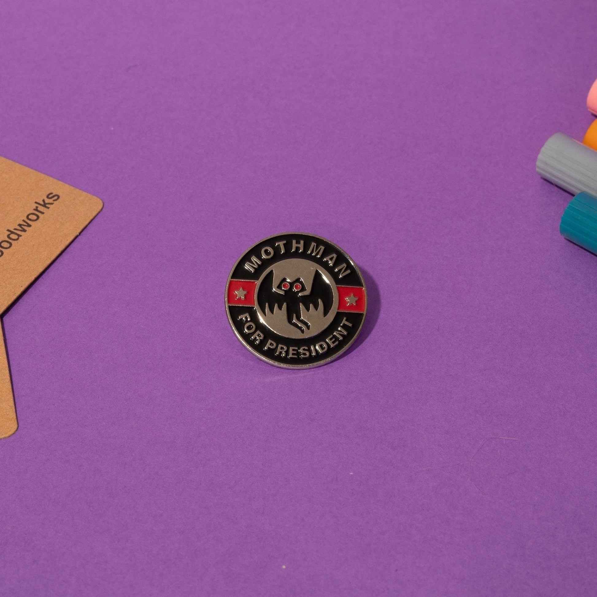 Enamel pin featuring Mothman with the bold text Mothman For President a perfect accessory for cryptid fans.