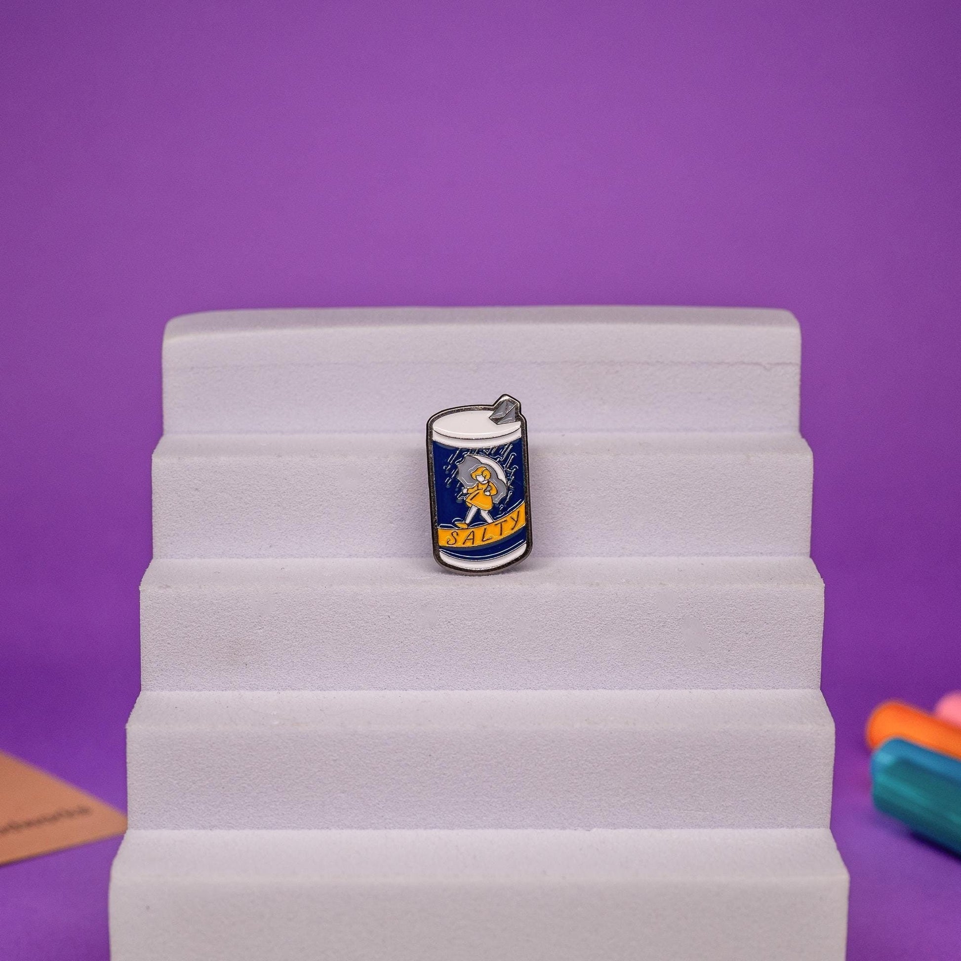Funny enamel pin featuring a salt-themed design with the word Salty ideal for quirky accessories.