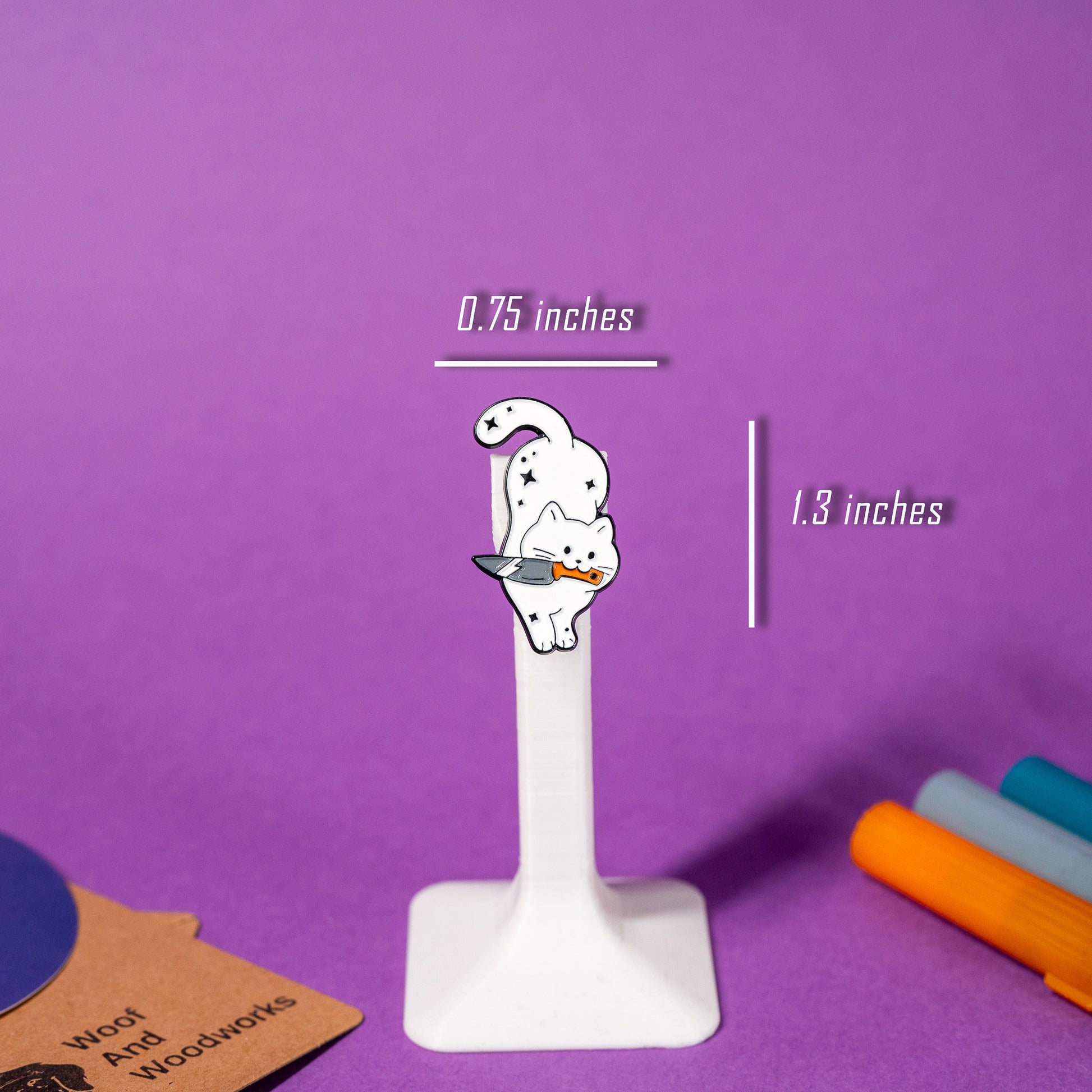 Dynamic enamel pin of a white cat leaping with a knife in its teeth, perfect for fans of playful and edgy designs.