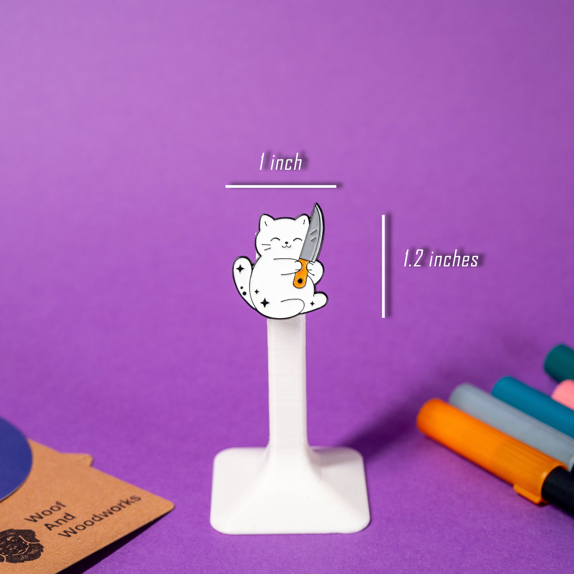Enamel pin of a white cat hugging a knife with a cheerful smile, perfect for quirky accessory fans.