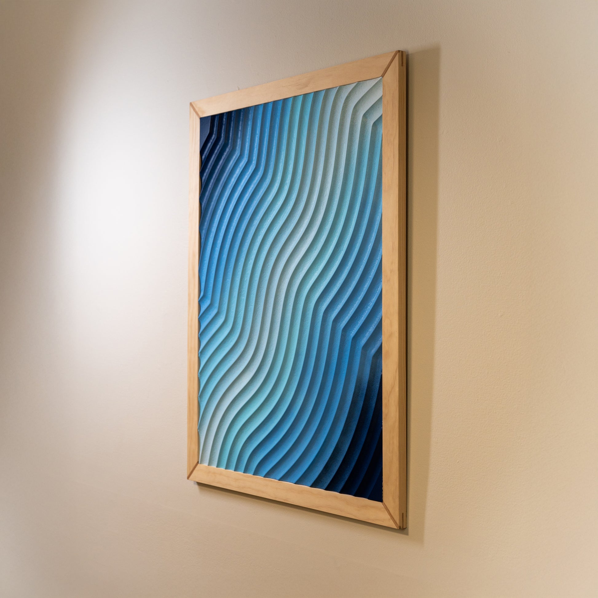 Right-side angle of the blue layered wave art, showing light reflection across carved ridges.