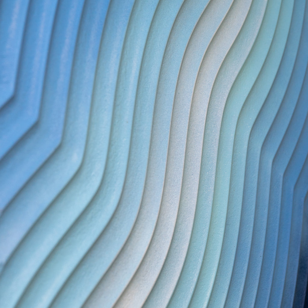 Macro photo of carved MDF layers in blue gradient paint, showing detailed texture and satin finish.