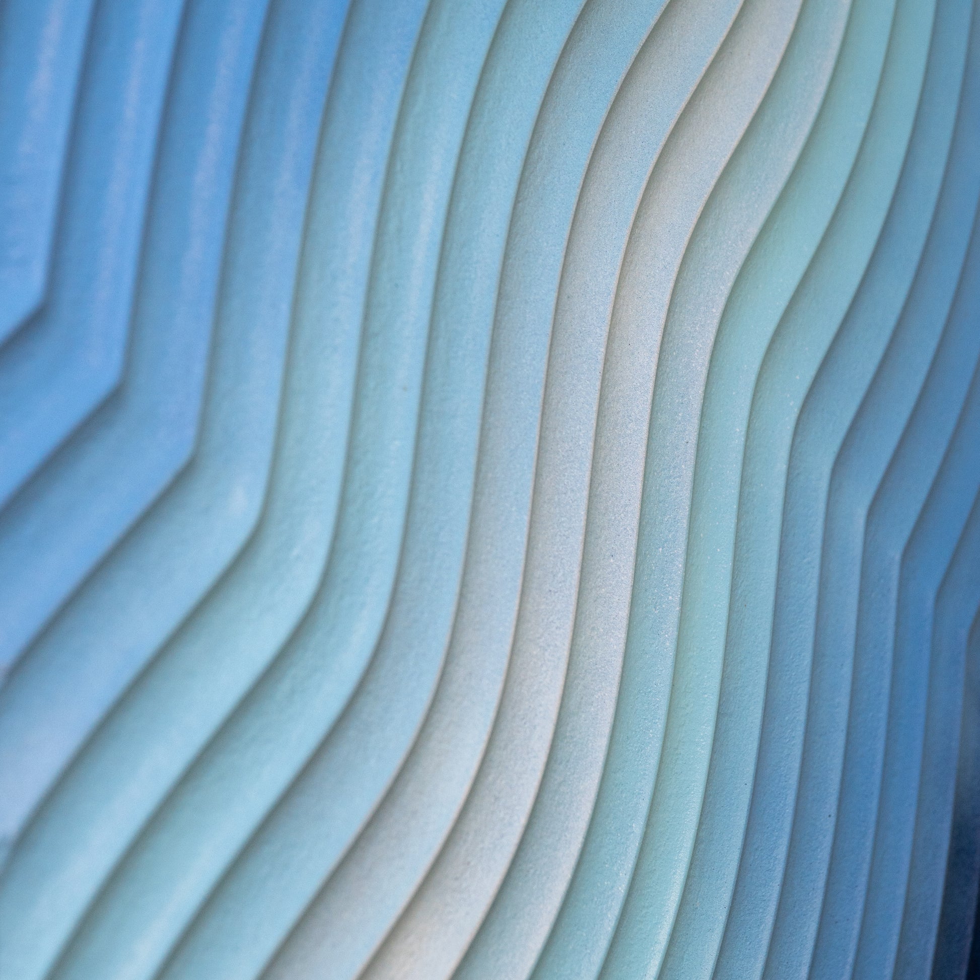 Macro photo of carved MDF layers in blue gradient paint, showing detailed texture and satin finish.