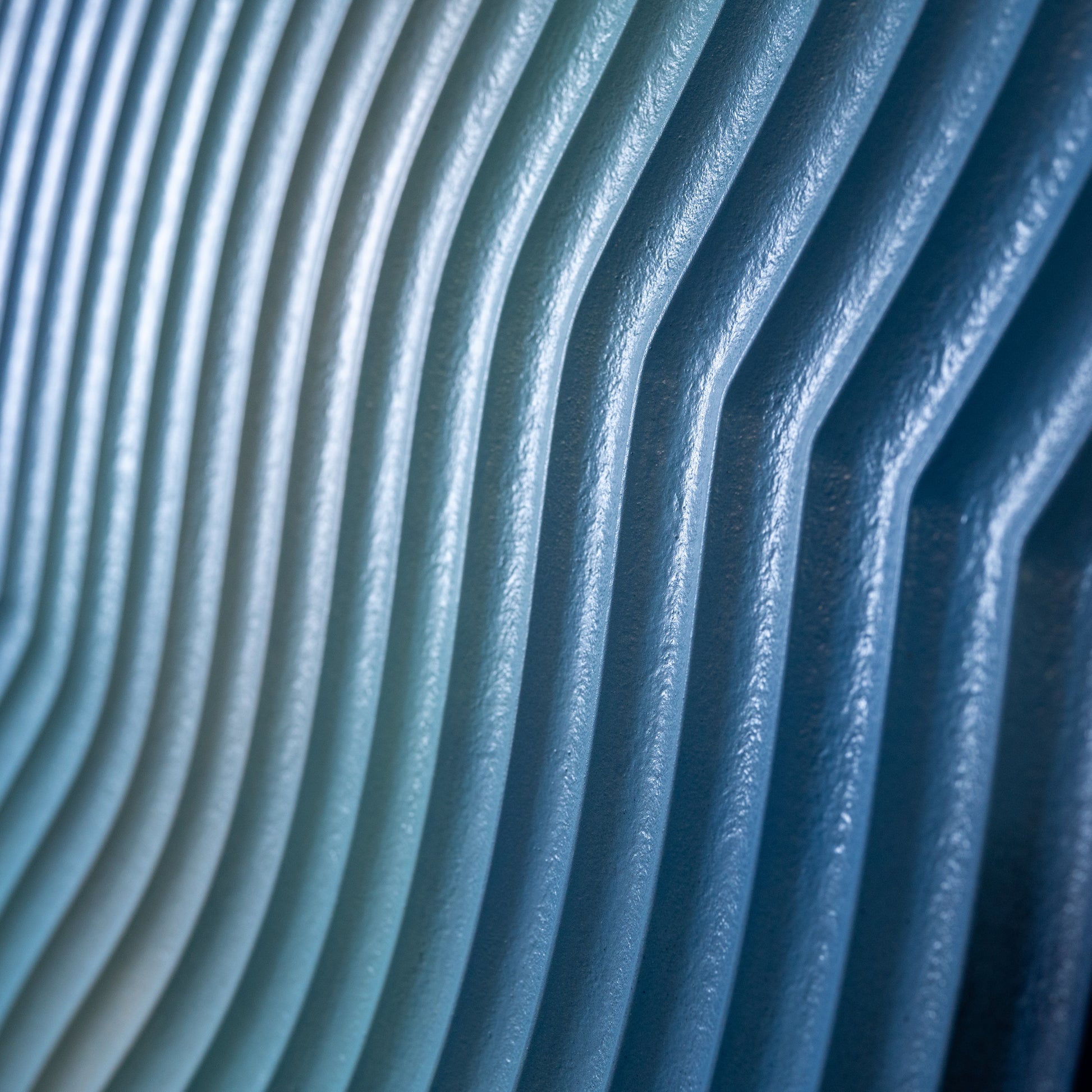 Macro photo of carved MDF layers in blue gradient paint, showing detailed texture and satin finish.