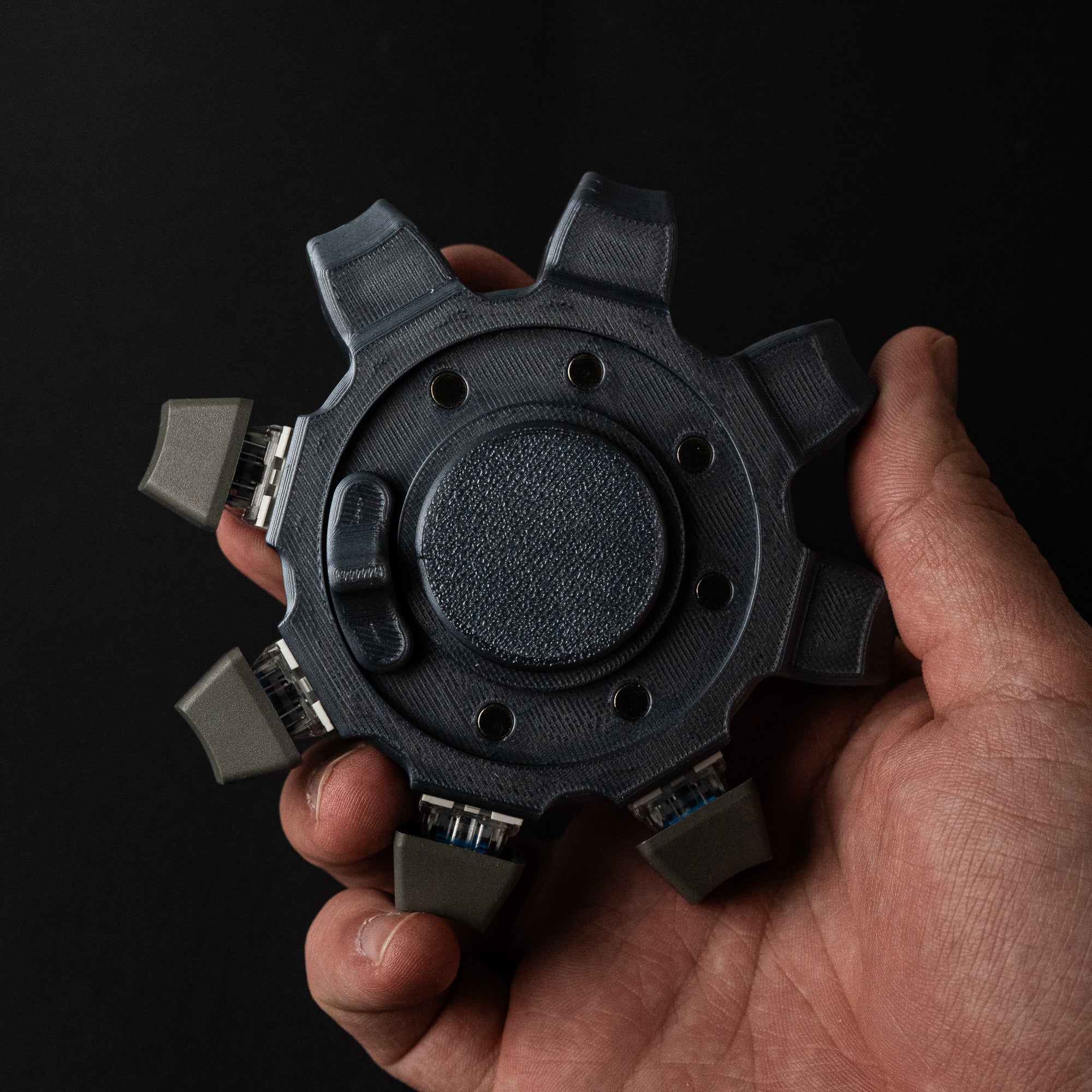 Mechanical cog fidget spinner held in hand showing palm size and industrial gear design.