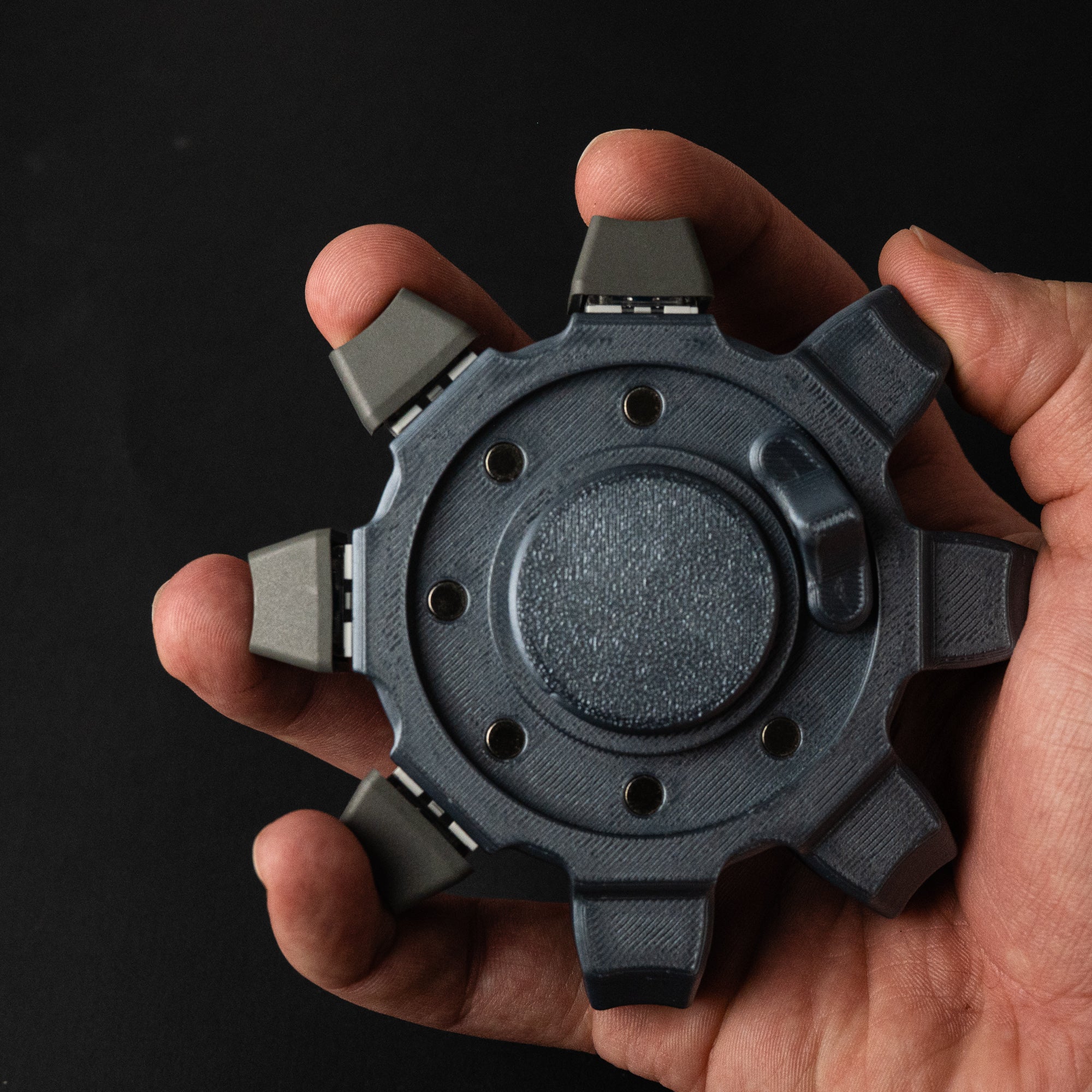 Industrial desk fidget held in hand demonstrating ergonomic grip and mechanical structure.