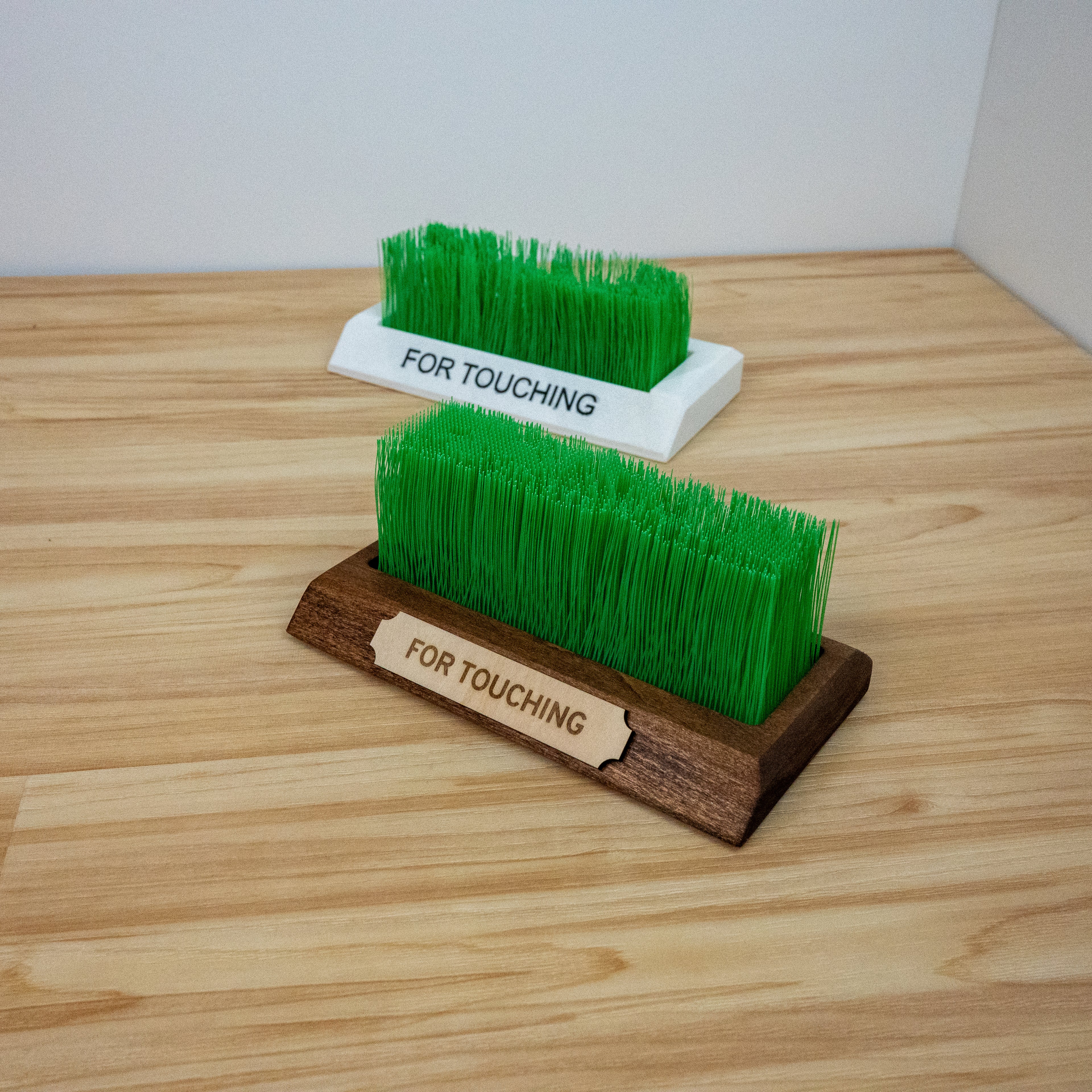 Close-up of touch grass desk accessory showing realistic green grass bristles