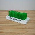 3D printed touch grass desk accessory with white plastic base and “FOR TOUCHING” label