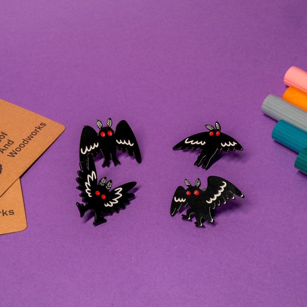 Enamel pin featuring Mothman, the mysterious cryptid creature, with intricate wing details and bold design.