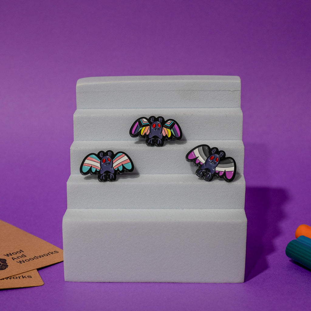 Enamel pin featuring Mothman with the LGBTQ+ pride flag design, perfect for celebrating diversity and cryptid charm.
