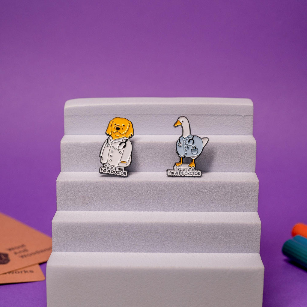 Set of funny doctor-themed enamel pins featuring a golden retriever and a duck, each with humorous text.