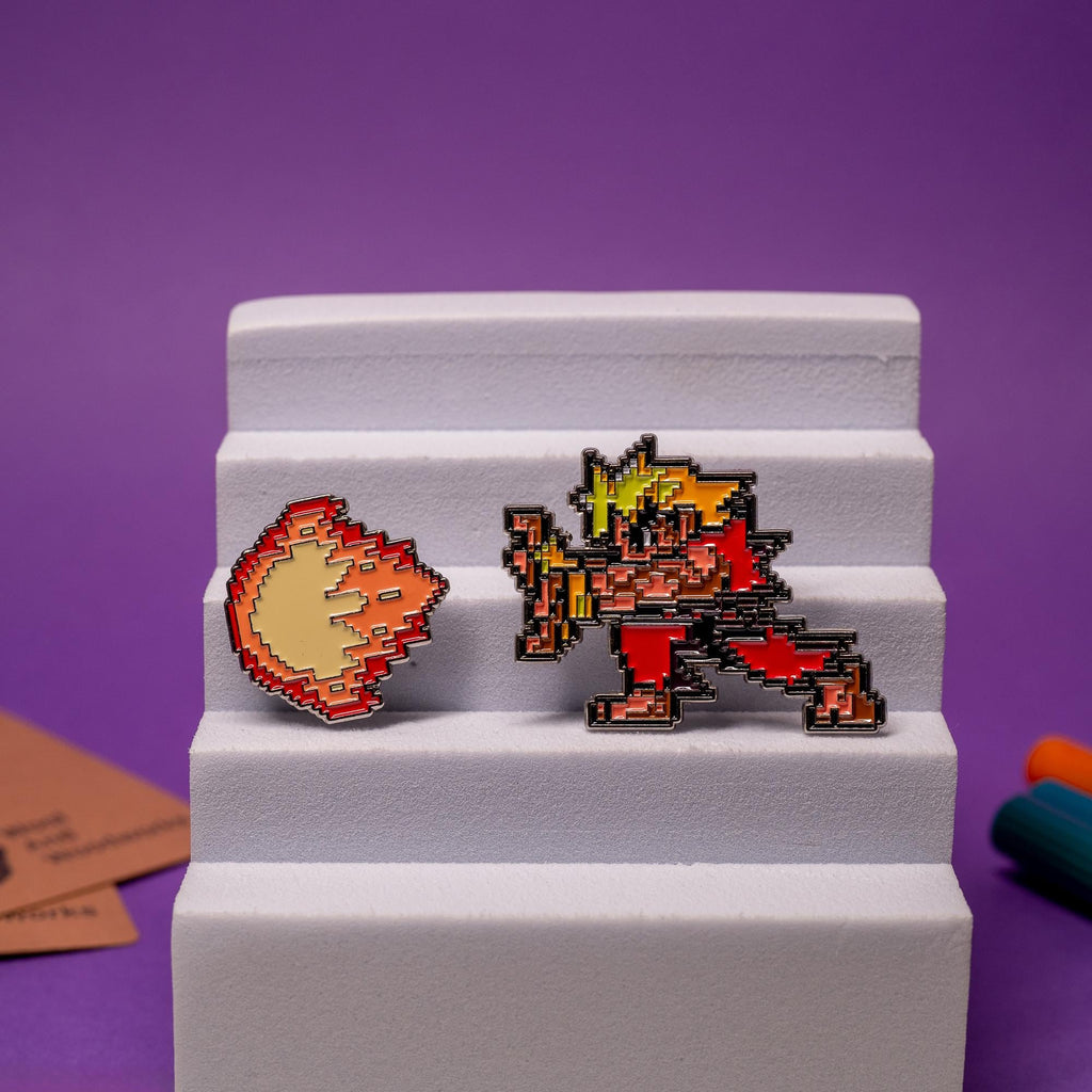 Street Fighter enamel pin set displayed together, featuring Akuma and Ken with their matching fireballs.
