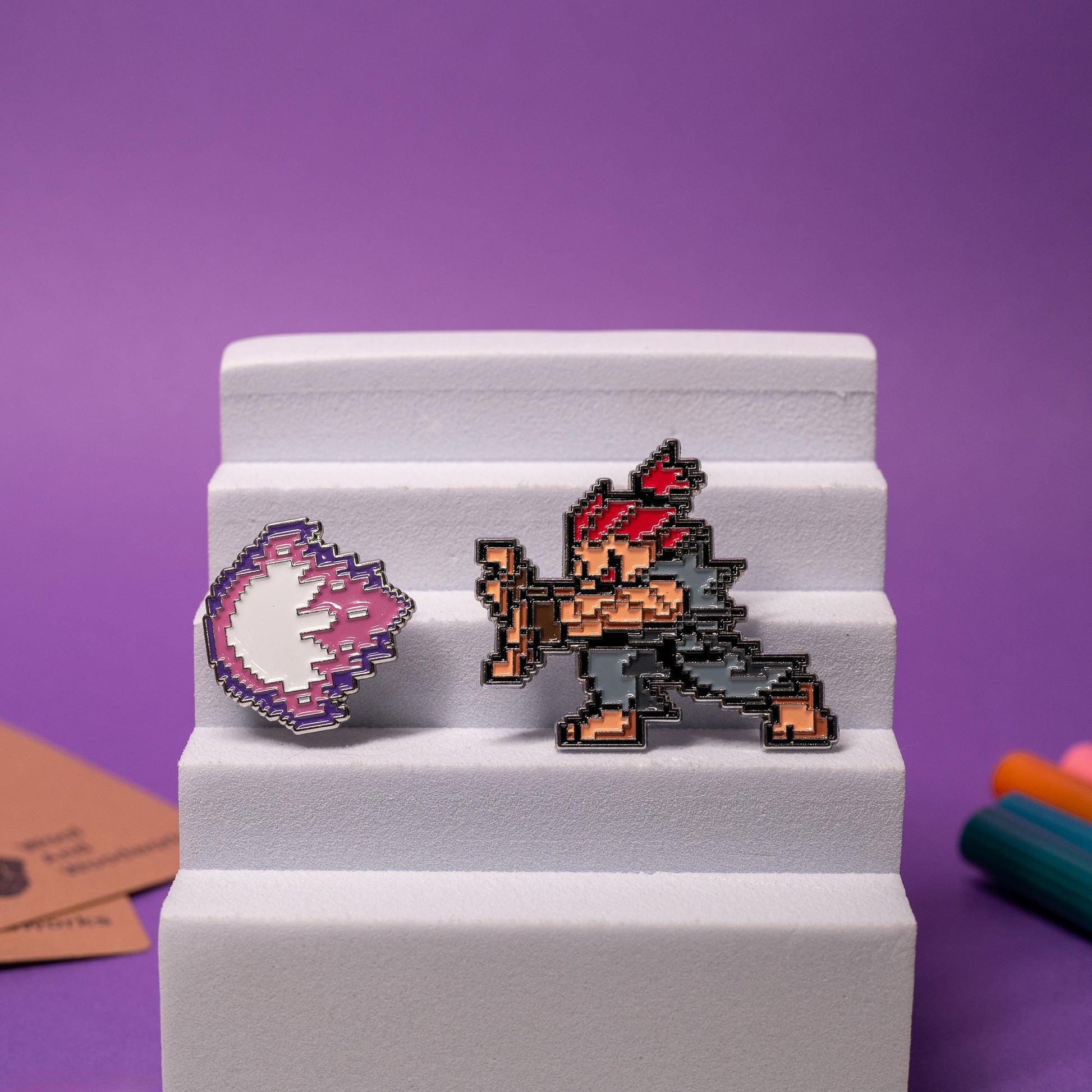 Street Fighter enamel pin set displayed together, featuring Akuma and Ken with their matching fireballs.