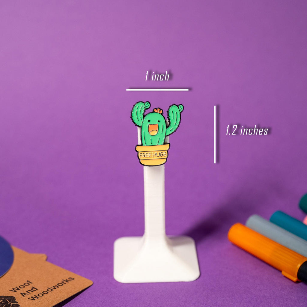 Funny enamel pin of a potted cactus with an open-mouthed smile and the text Free Hugs.