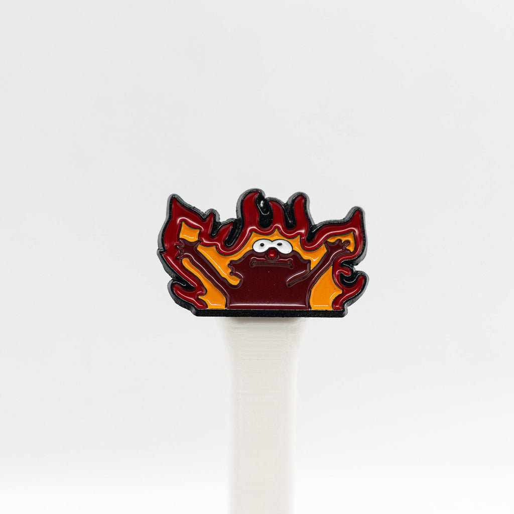 Close-up of the Hellmo enamel pin featuring the iconic fire puppet meme, showcasing bright red and orange flames with bold detailing.