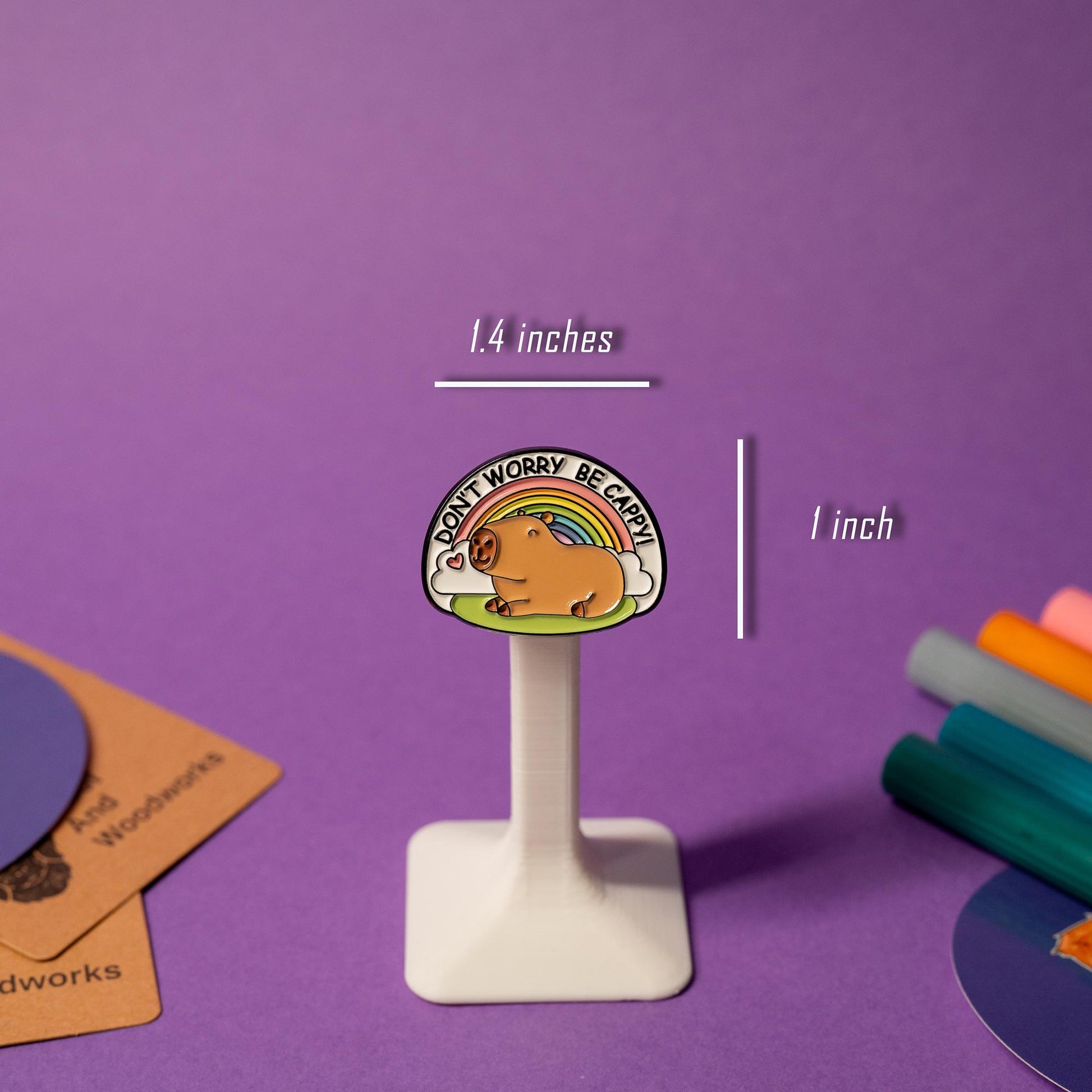 Enamel pin featuring a capybara with a rainbow in the background and the text Don’t Worry Be Cappy!
