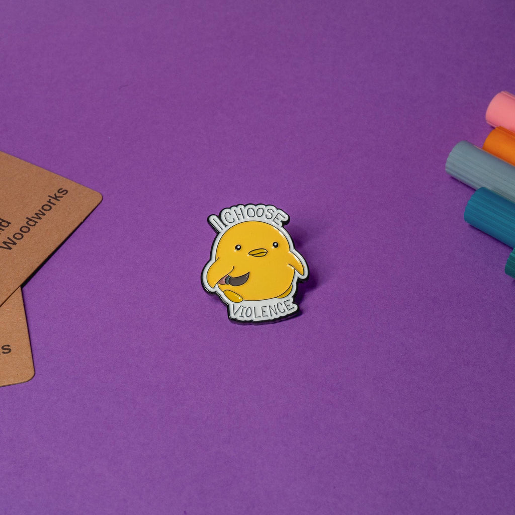 Enamel pin featuring a duck holding a knife with the humorous text I Choose Violence.