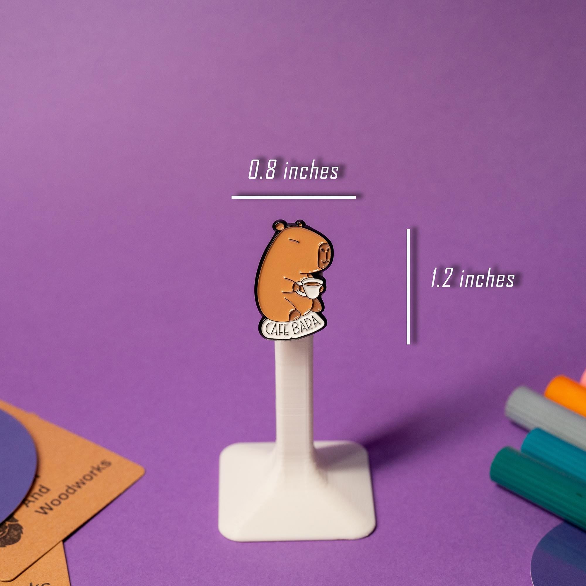 Close-up of the Cafe Bara enamel pin, featuring a capybara holding a coffee cup.