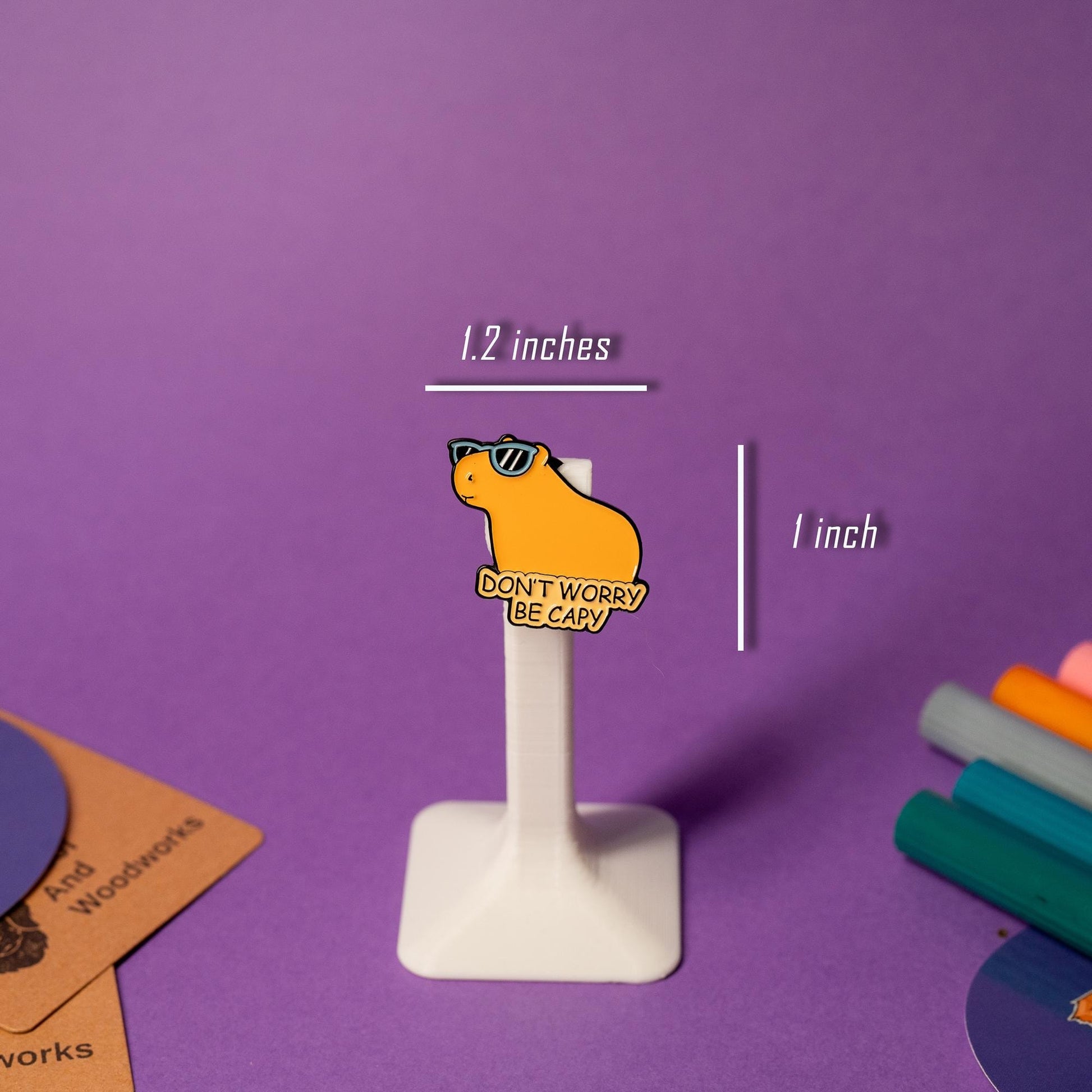 Close-up of the Dont Worry Be Capy enamel pin, featuring a capybara in a relaxed pose with cheerful text and a bright design.