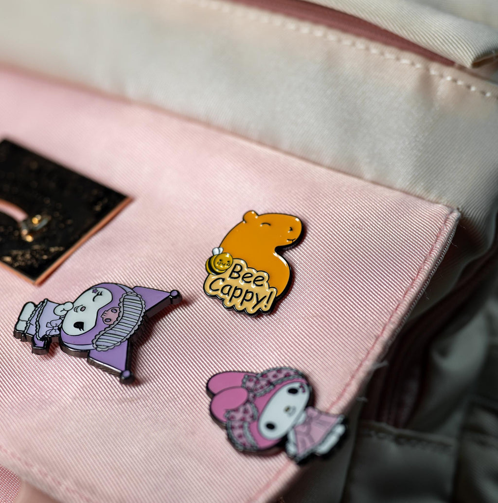 Friendly Capybara enamel pin attached to a backpack, highlighting its vibrant design and portability as a fun accessory.