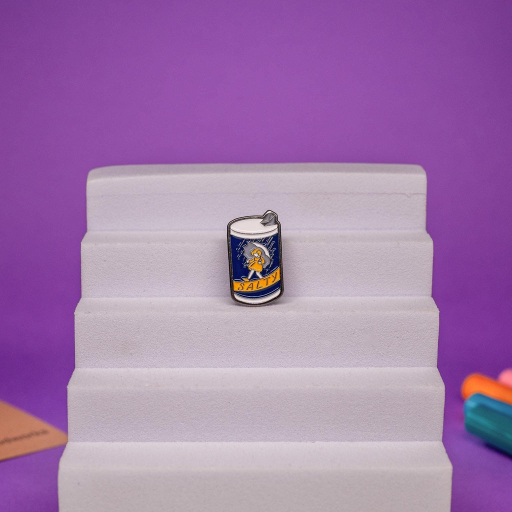Funny enamel pin featuring a salt-themed design with the word Salty ideal for quirky accessories.