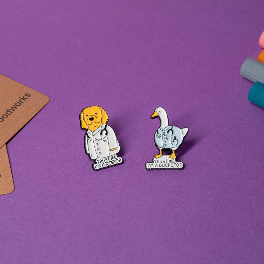 Set of funny doctor-themed enamel pins featuring a golden retriever and a duck, each with humorous text.