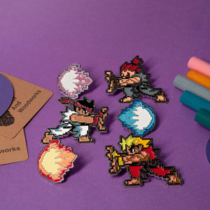 Set of 2 enamel pins featuring pixelated Street Fighter characters and their iconic fireballs.