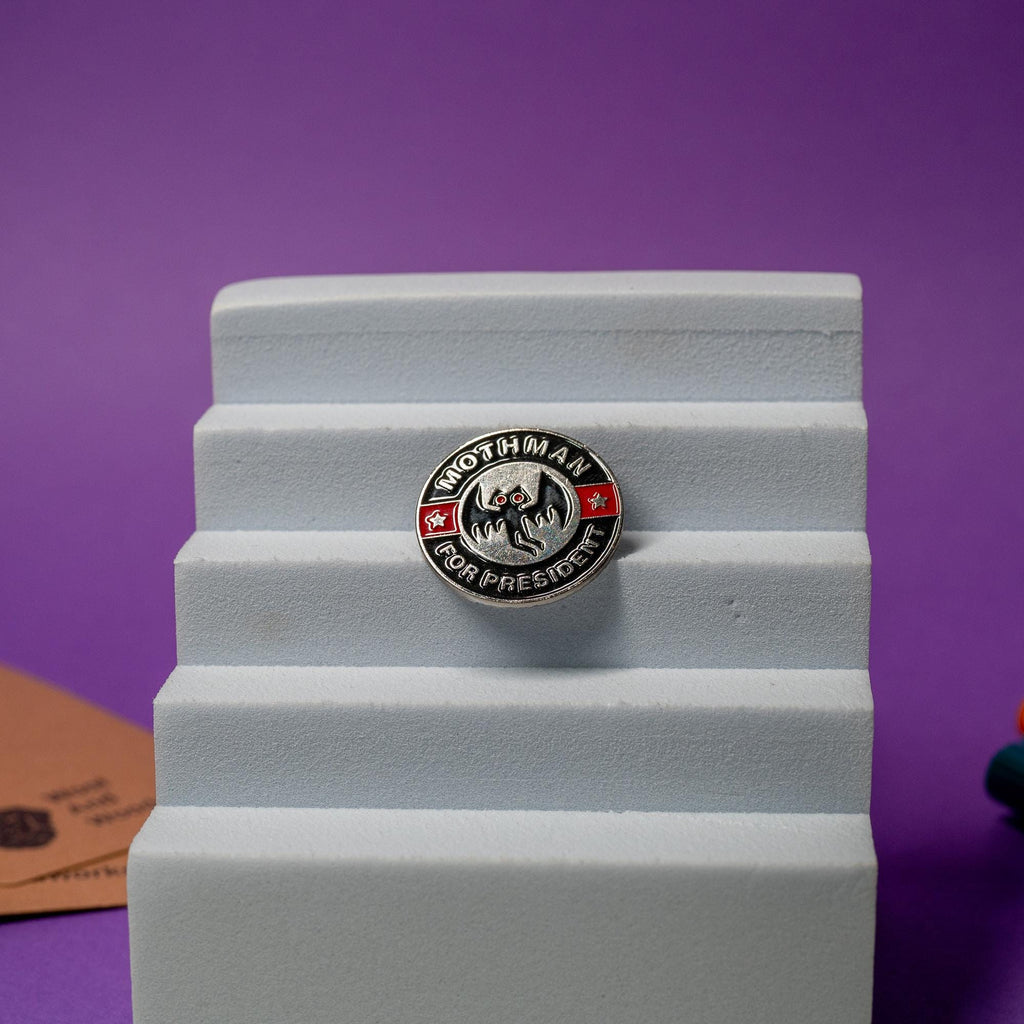 Close-up of Mothman enamel pin with the humorous slogan Mothman For Presidentideal for quirky collections.