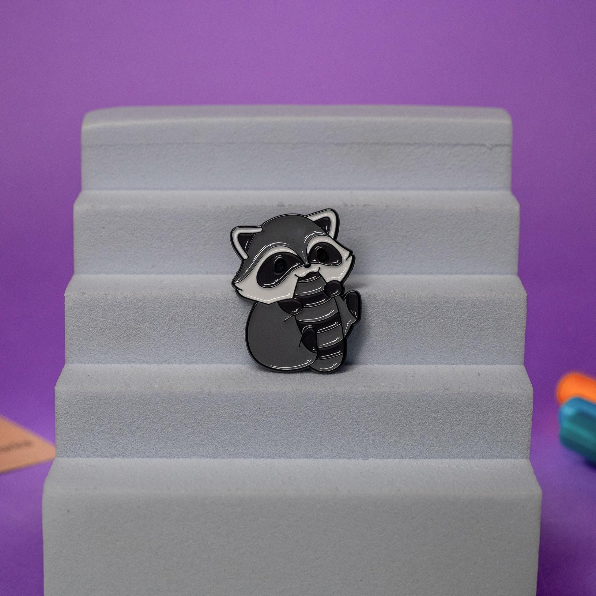 Cute raccoon enamel pin displayed on a jacket, ideal for animal enthusiasts and quirky accessory fans.