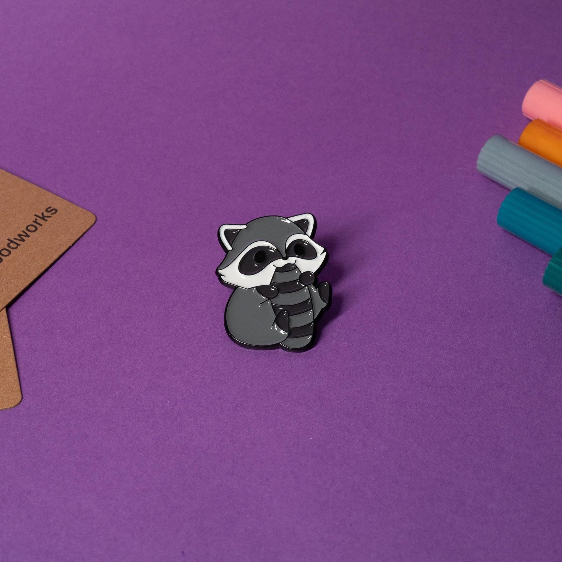 Enamel pin featuring a cute raccoon with an adorable design, perfect for animal lovers and pin collectors.