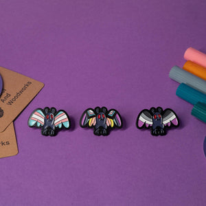 Enamel pin featuring Mothman with the LGBTQ+ pride flag design, perfect for celebrating diversity and cryptid charm.