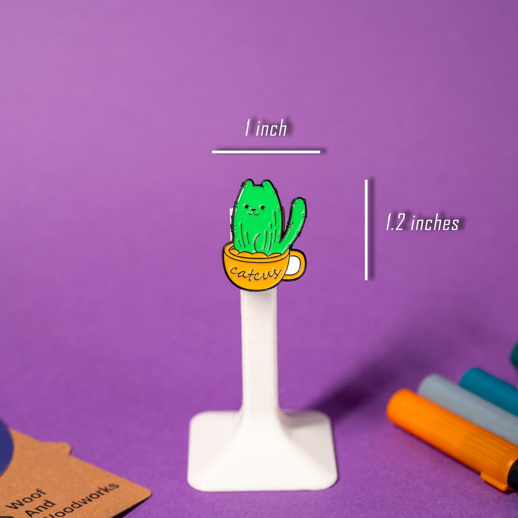 Adorable cactus enamel pin shaped like a cat, complete with a tail and the punny text Catcus.