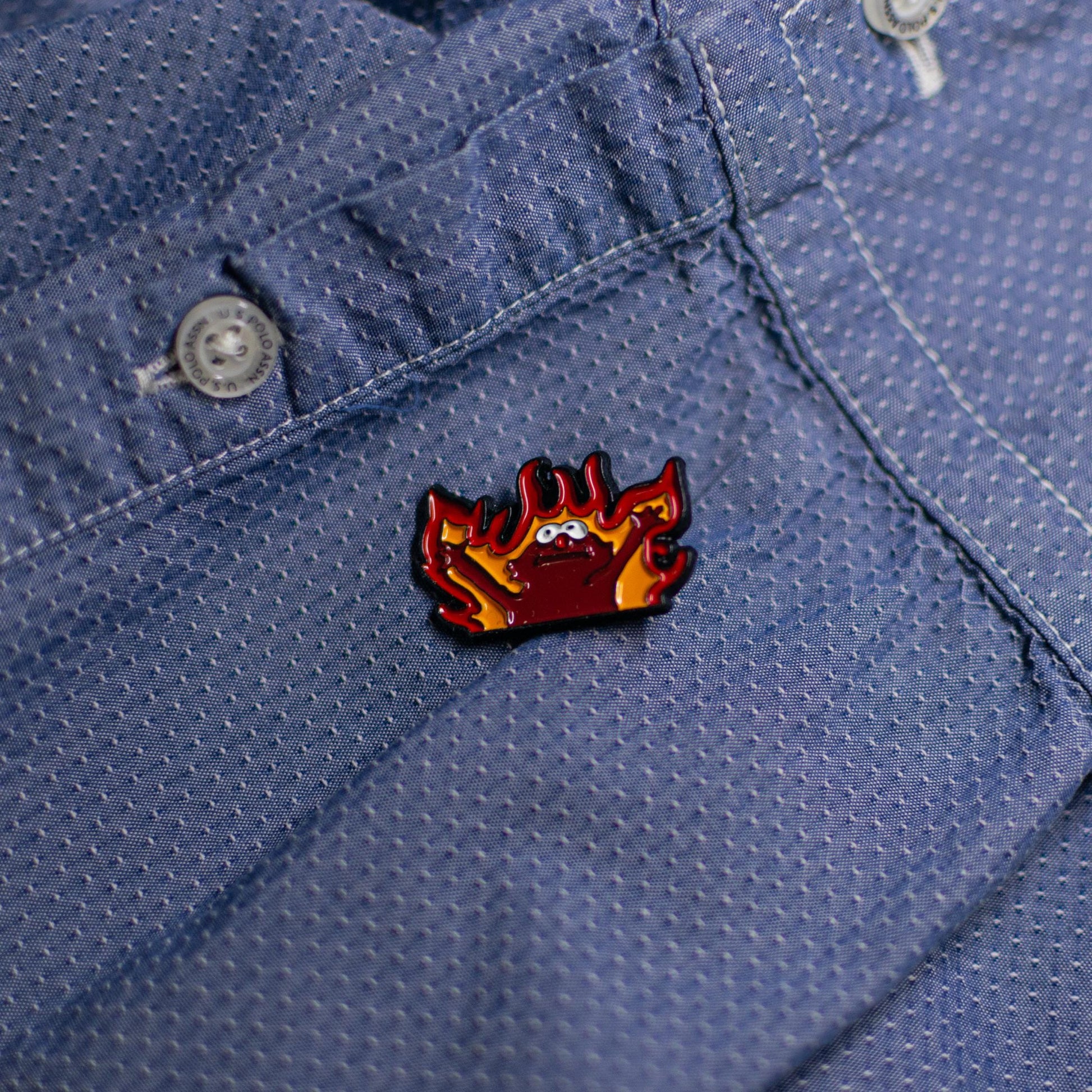 Close-up of the Hellmo enamel pin featuring the iconic fire puppet meme, showcasing bright red and orange flames with bold detailing.