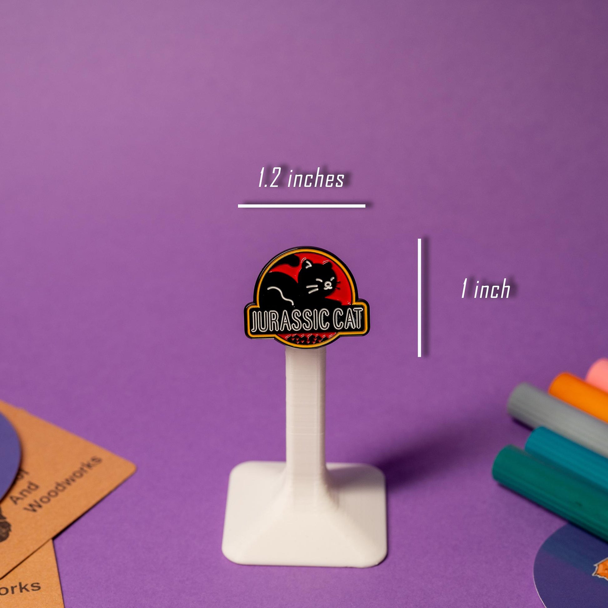 Parody enamel pin of the Jurassic Park logo with a black cat silhouette and the text Jurassic Cat.