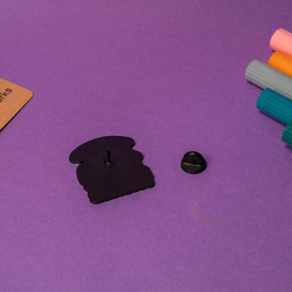 Close-up of enamel pin with a quirky cat scooping litter, showcasing the text Trying to get my sh*t together.