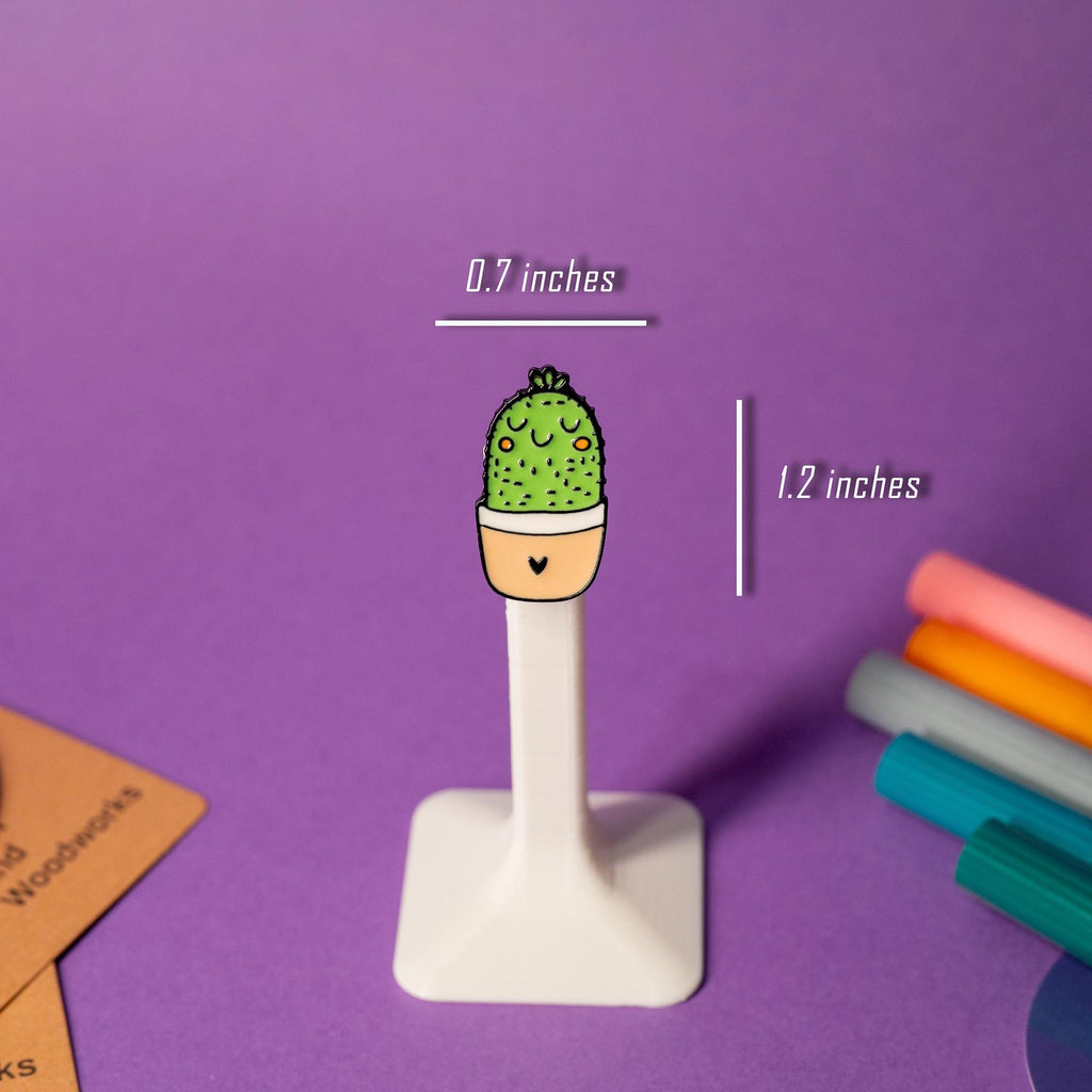 Enamel pin featuring a cute cactus with a happy face in vibrant green.