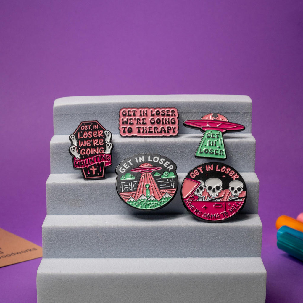 Set of 5 Get In Loser enamel pins featuring UFOs, skeletons, ghosts, and humorous phrases.