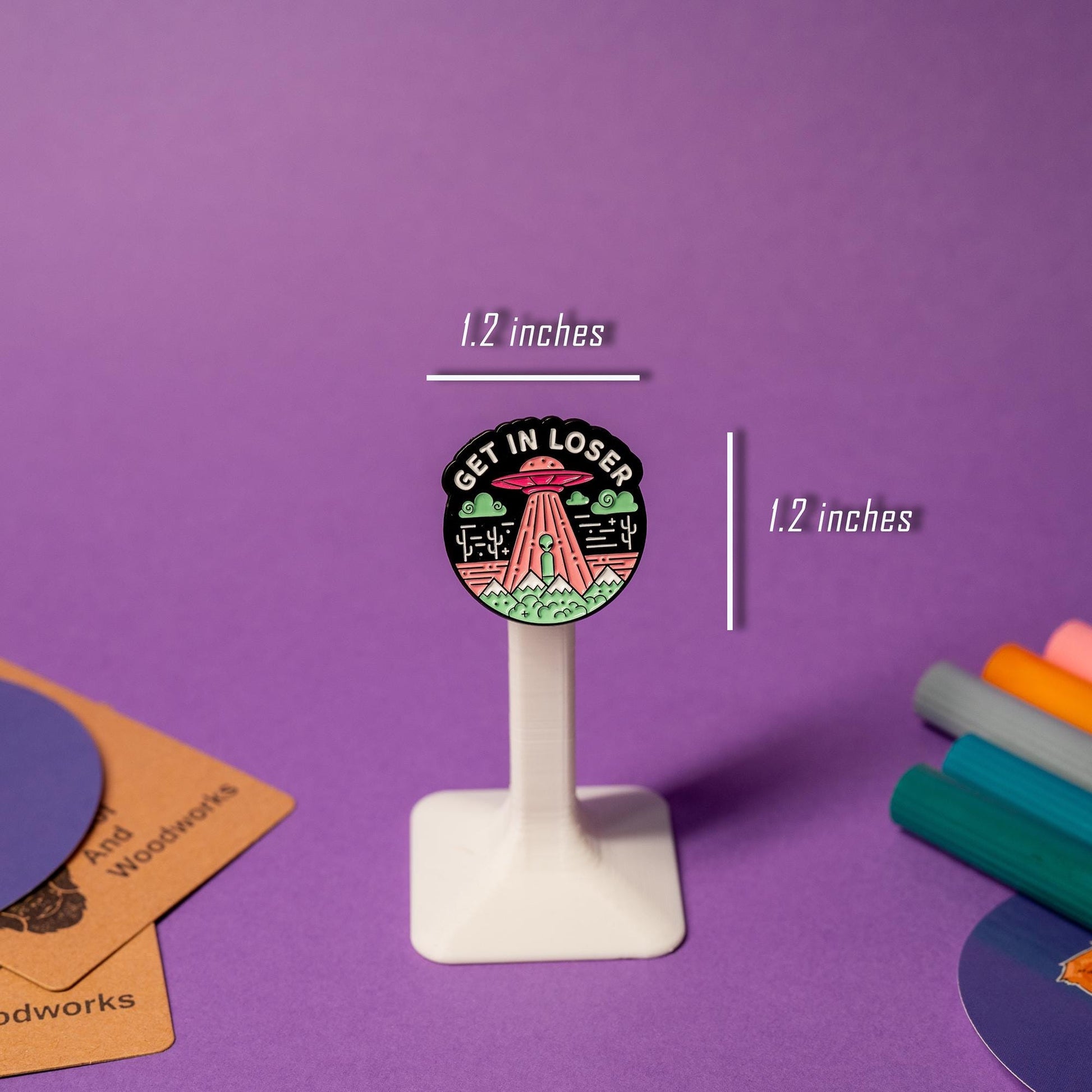 Enamel pin with a UFO and alien design featuring the phrase Get In Loser.