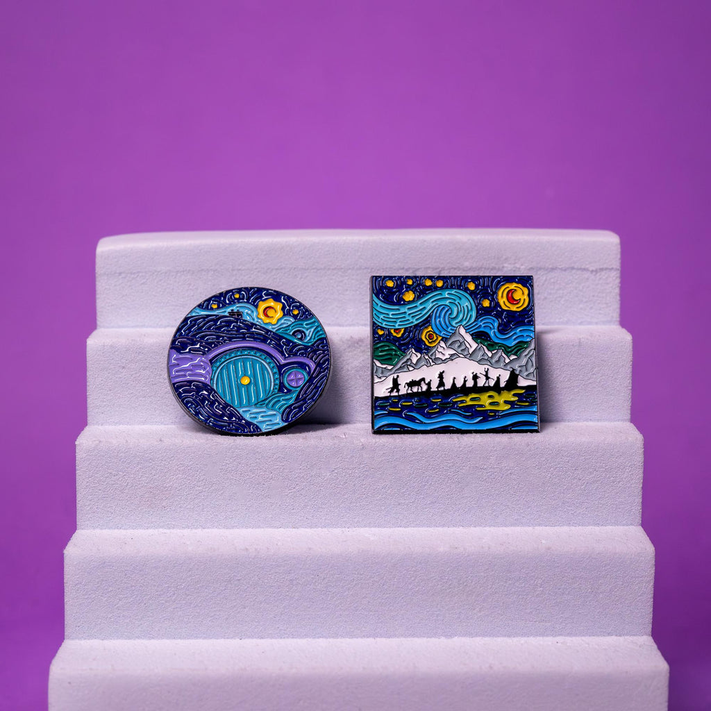 Lord of the Rings enamel pins displayed on a foam stand, featuring Starry Night-inspired designs of the Fellowship and the Hobbit’s door.