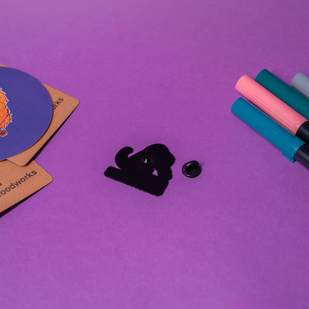 Back view of the T-Rex enamel pin, showing smooth metal finish and secure resin pinback.