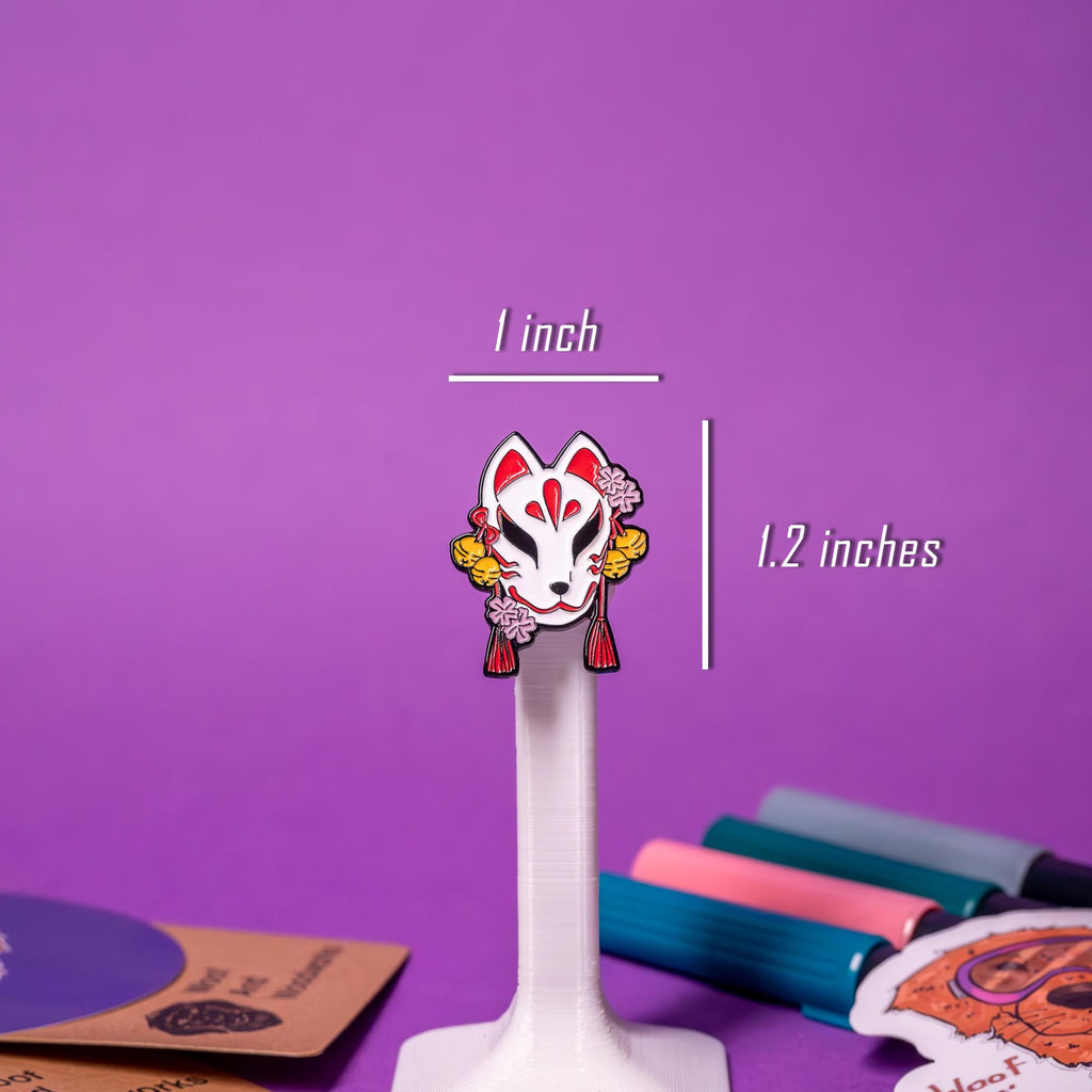 Close-up of the Kitsune mask enamel pin, showcasing the fine lines, vibrant colors, and unique fox mask design.