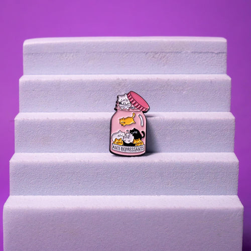 Anti Depressants enamel pin displayed on a foam stand, emphasizing its vibrant colors, playful design, and kawaii cat details.